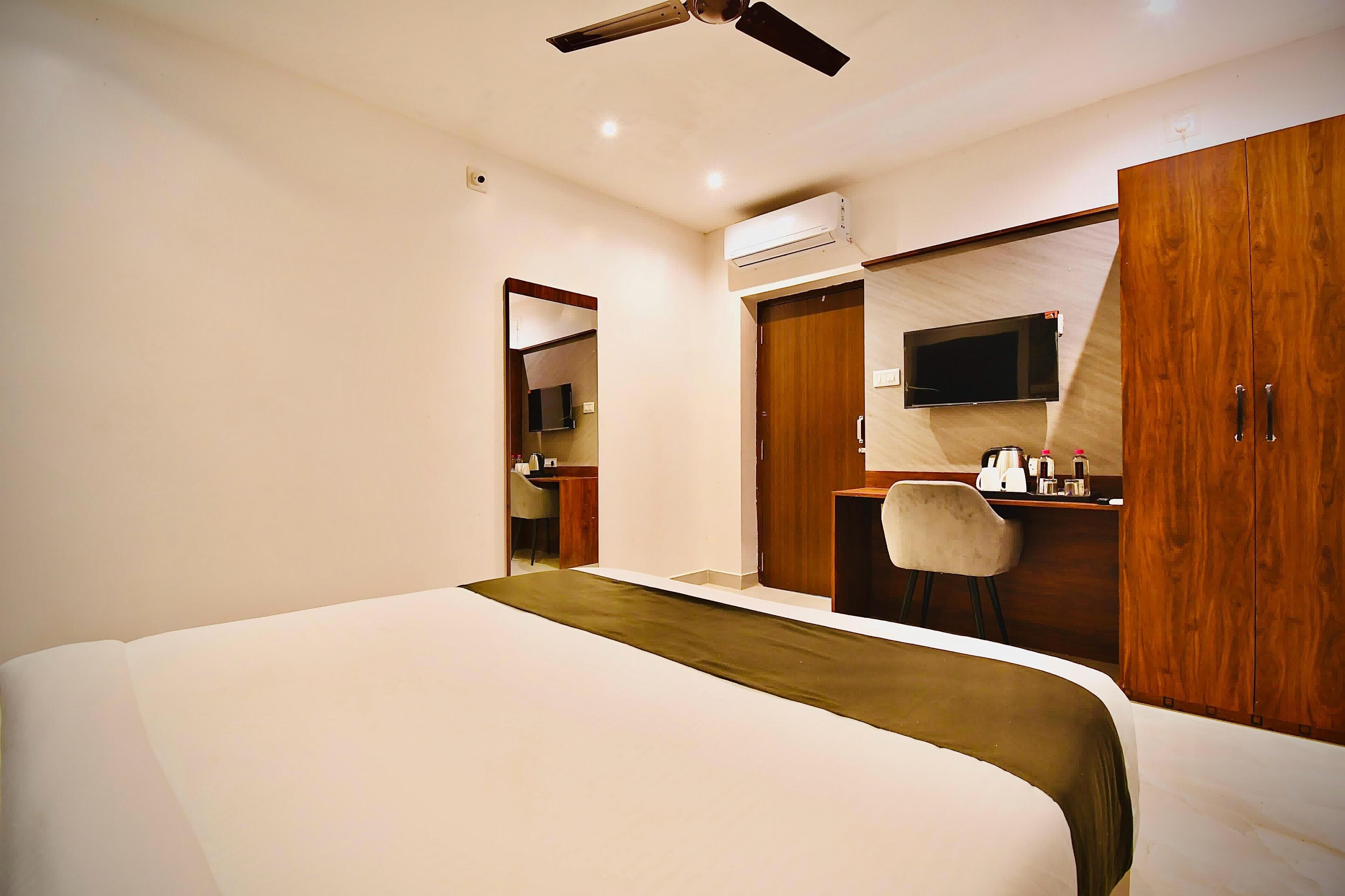 Une chambre d’hôtel moderne équipée d’un lit, d’un bureau, d’une chaise, d’une télévision et d’une armoire.
