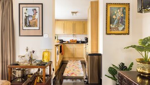A kitchen with wooden cabinets, a stainless steel refrigerator, and a countertop with various items. - Mayfair 3-bed 6-guest W/patio & ac Berkeley Square (London)
