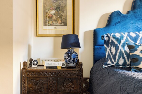 A neatly arranged bedside table with a lamp, a framed picture, and some books.