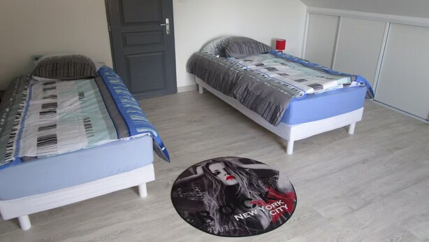A room with two beds, a door, and a circular rug with a cityscape design. - Maison Jardin Clos & Animaux Bienvenus - Near Lake & GR12 🐾 (Bourg-Fidèle)
