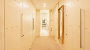 A narrow hallway with beige walls and a tiled floor leading to a bathroom with a shower and a mirror. - Large 4-bed 8-guests W/patio 1841 House Paddington (London)