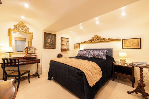 A bedroom with a large bed, a wooden desk, a chair, a nightstand, and a mirror. - Large 4-bed 8-guests W/patio 1841 House Paddington (London)