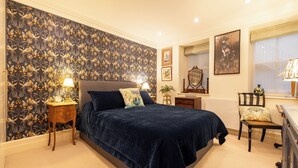 A bedroom with a large bed, a nightstand, a chair, a dresser, and a window with a view. - Large 4-bed 8-guests W/patio 1841 House Paddington (London)