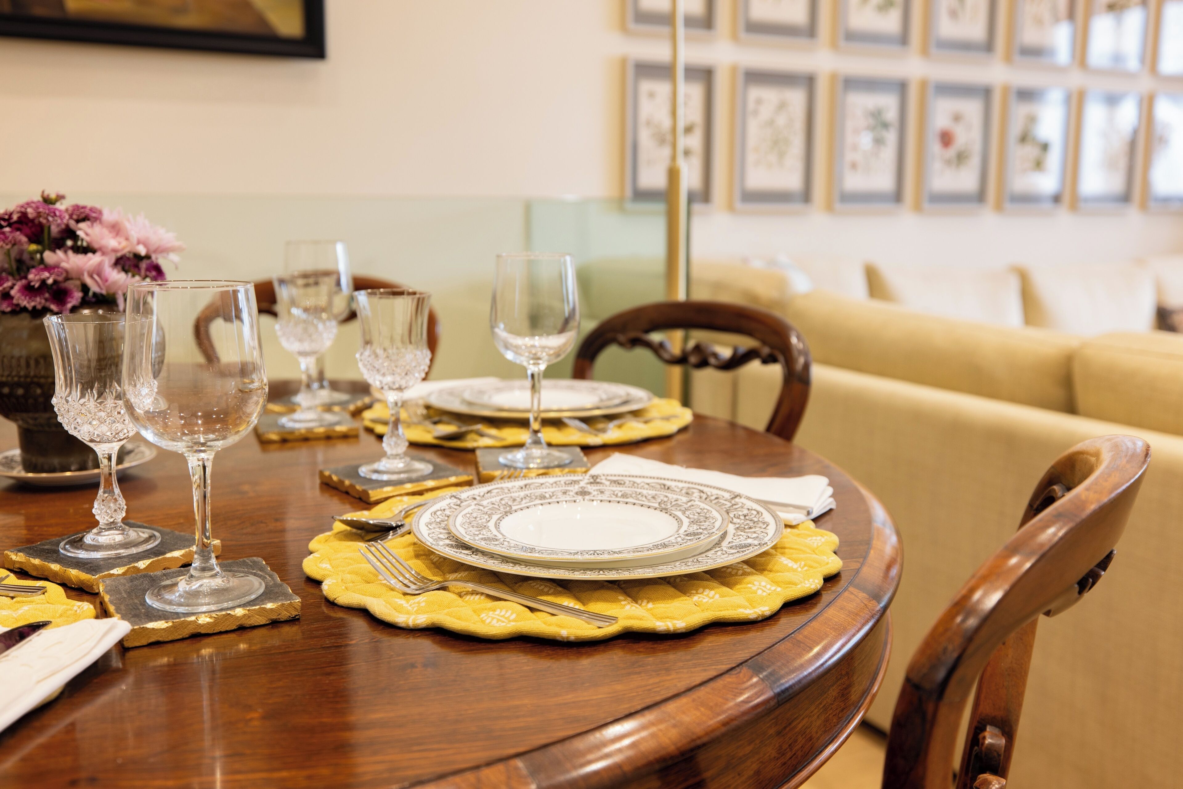 A dining table set with plates, glasses, and cutlery, surrounded by chairs.