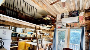 L’intérieur d’un chalet rustique comprend une cuisine, un coin repas et un balcon offrant une vue panoramique.