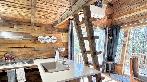 Une cuisine rustique avec des poutres en bois, un plan de travail blanc, un évier et une bouilloire.