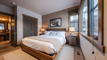 A bedroom with a large bed, wooden wardrobe, and a window with a view.