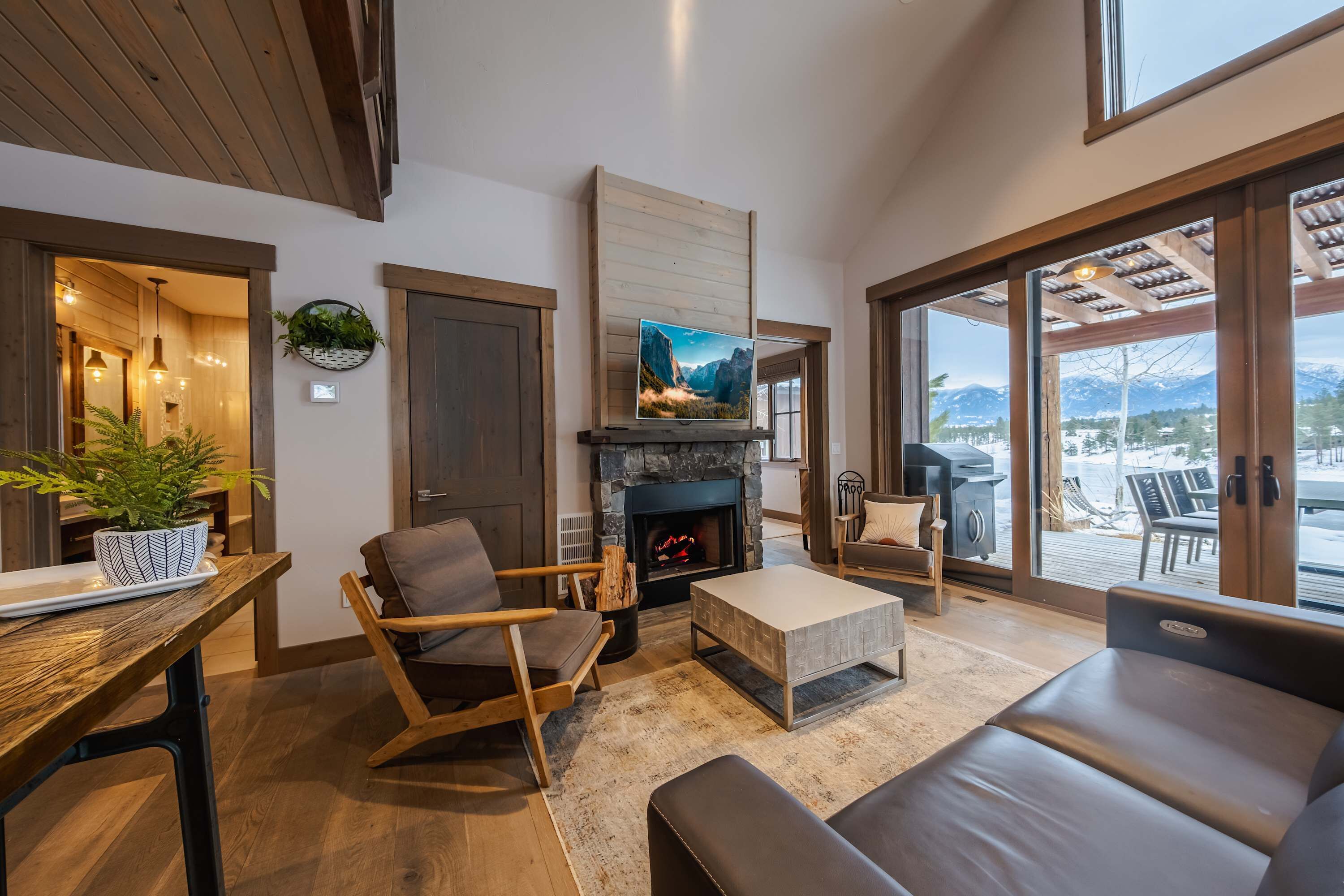 A cozy living room with a fireplace, comfortable seating, a television, and a view of the outdoors.