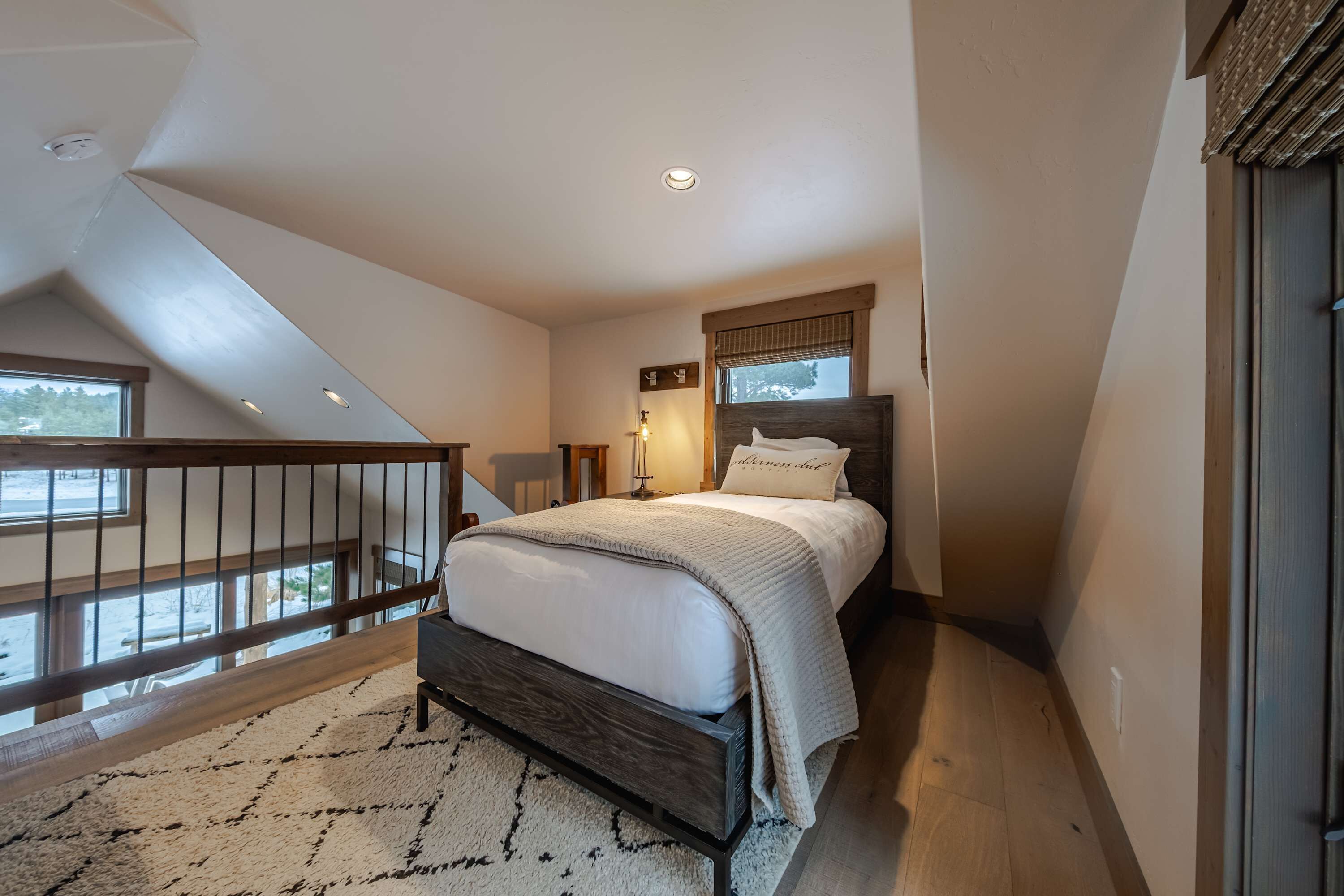A bedroom with a bed, a nightstand, a lamp, and a window.
