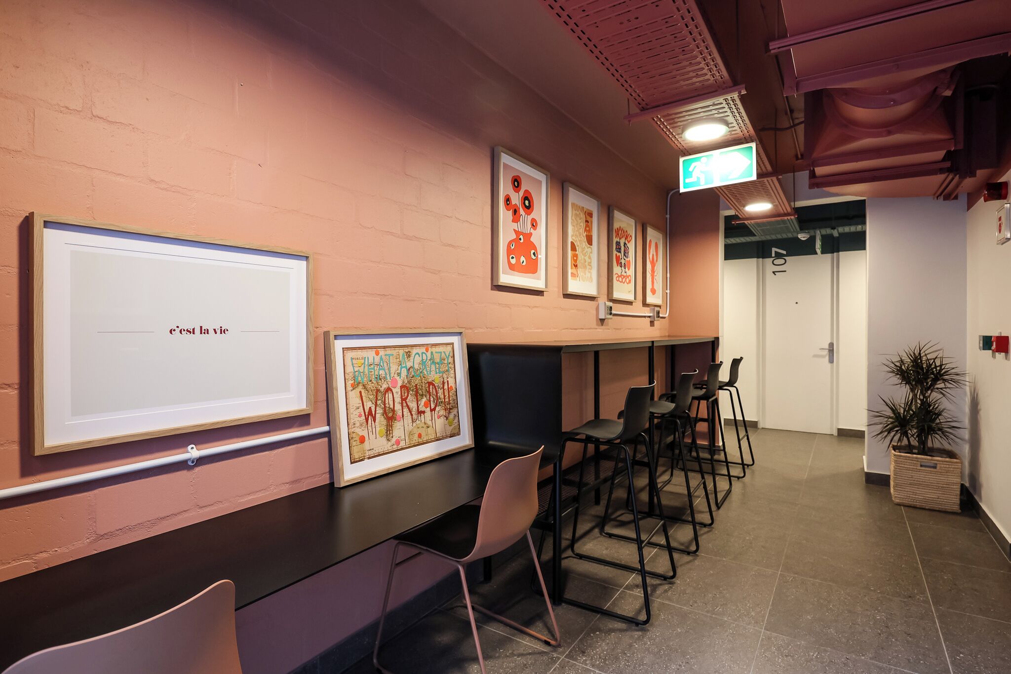Une salle de conférence équipée d’un tableau blanc, de tableaux décoratifs et de chaises noires.