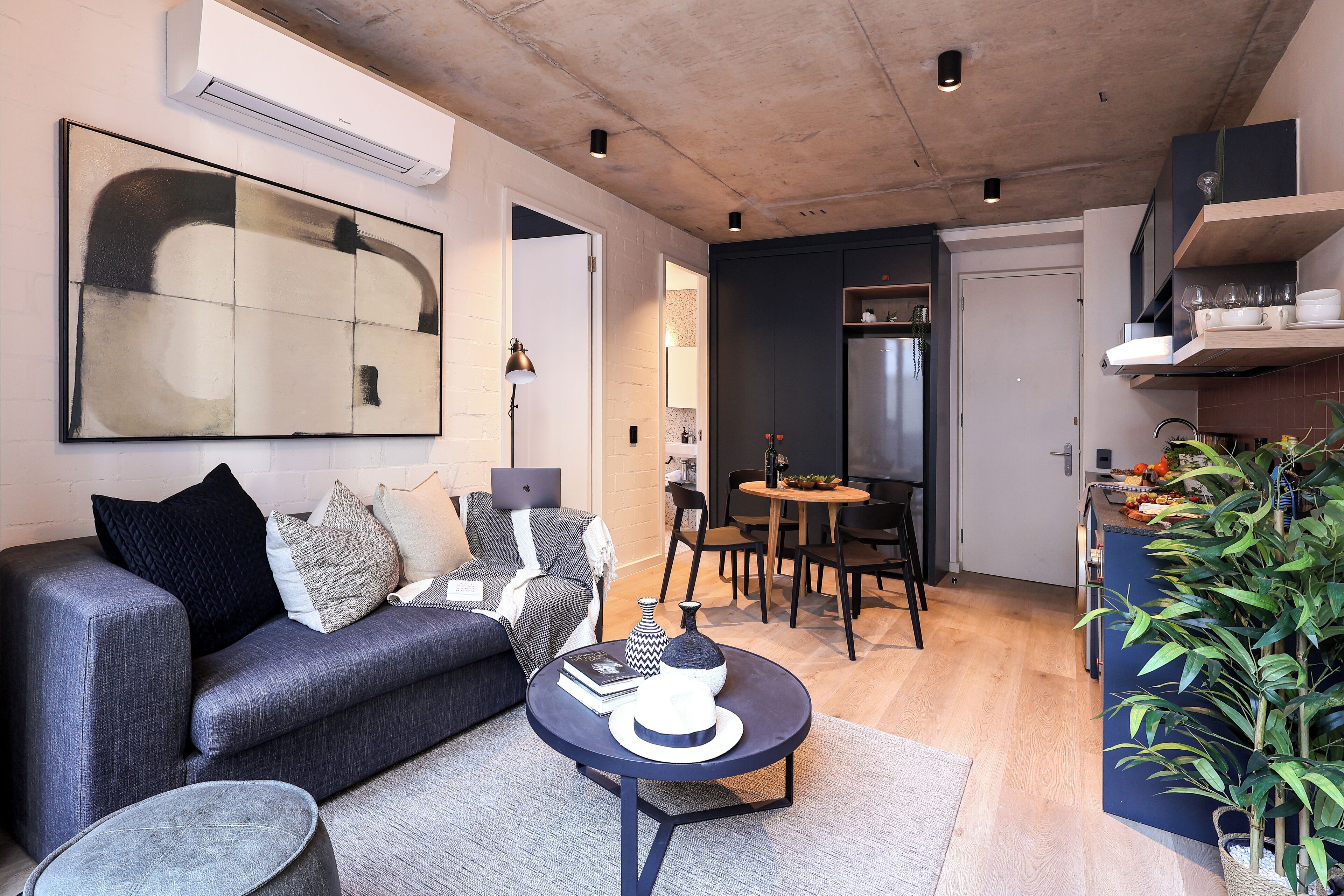 A modern living room with a grey sofa, a round coffee table, and a large abstract painting.