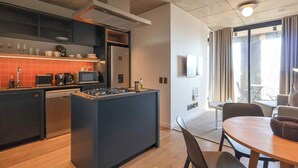 Une cuisine moderne dotée d’un îlot central, d’appareils électroménagers intégrés et d’un coin repas avec une table et des chaises.