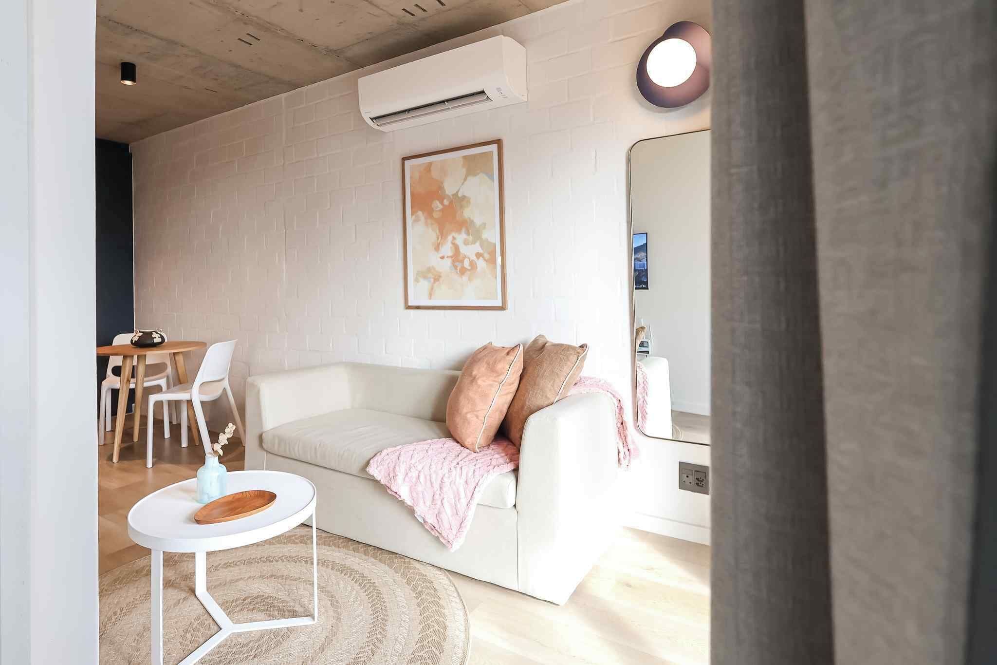 Un salon moderne avec un canapé blanc, une petite table ronde et un miroir.