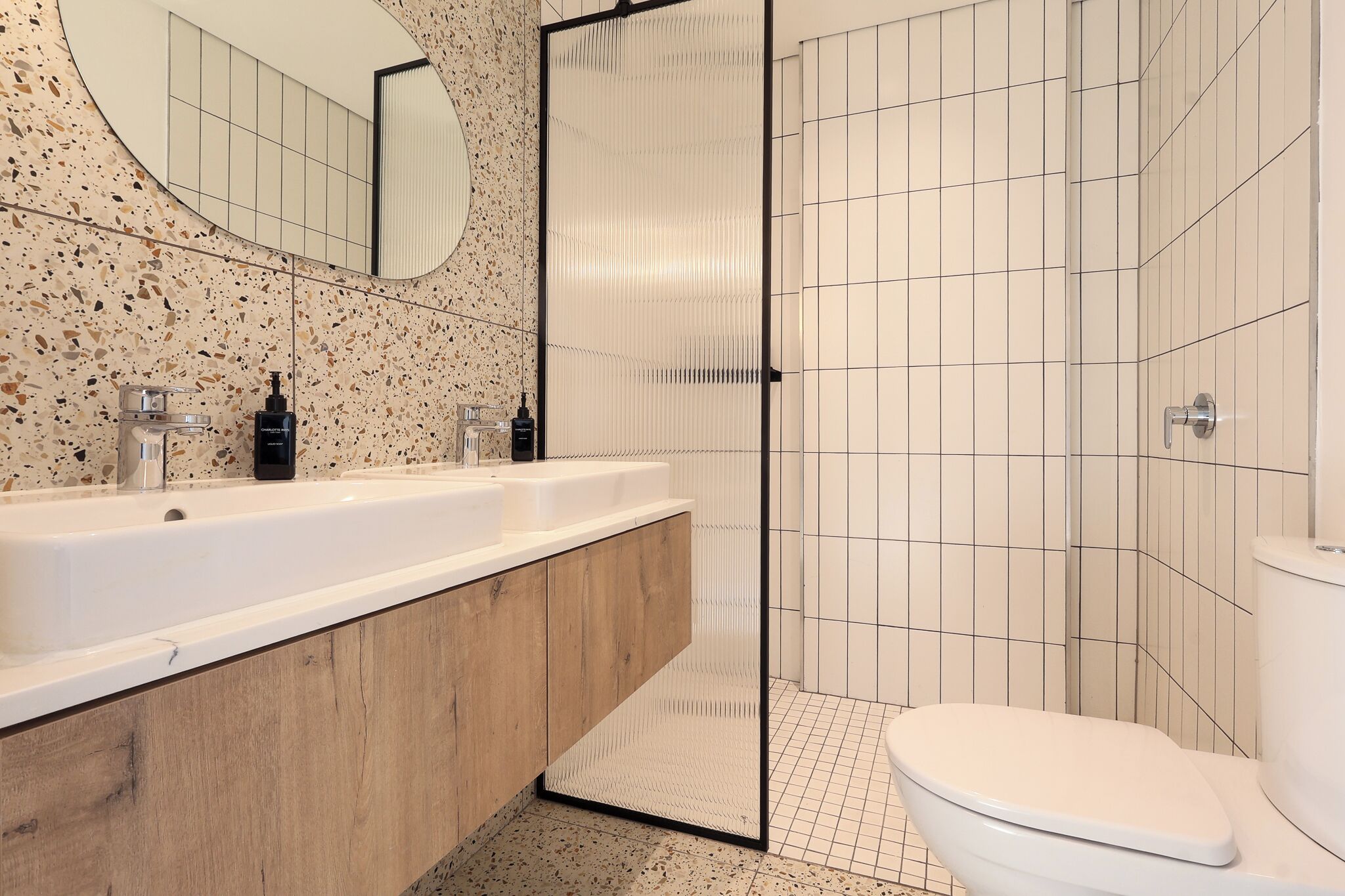Un bagno moderno con una vasca da bagno indipendente, un mobile contenitore in legno, un ampio specchio e cabina doccia.