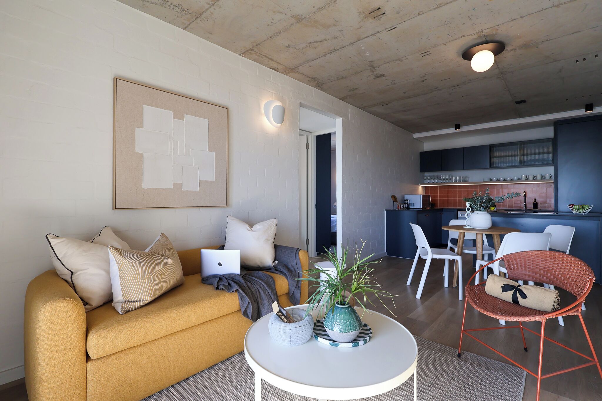 A modern living room with a sofa, a coffee table, and a dining area with chairs.