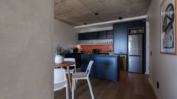 Una cocina moderna con una isla central, un comedor con una mesa redonda y sillas, y un refrigerador grande.