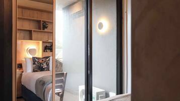 A bedroom with a bed, bedside table, lamp, and a view through a glass door.