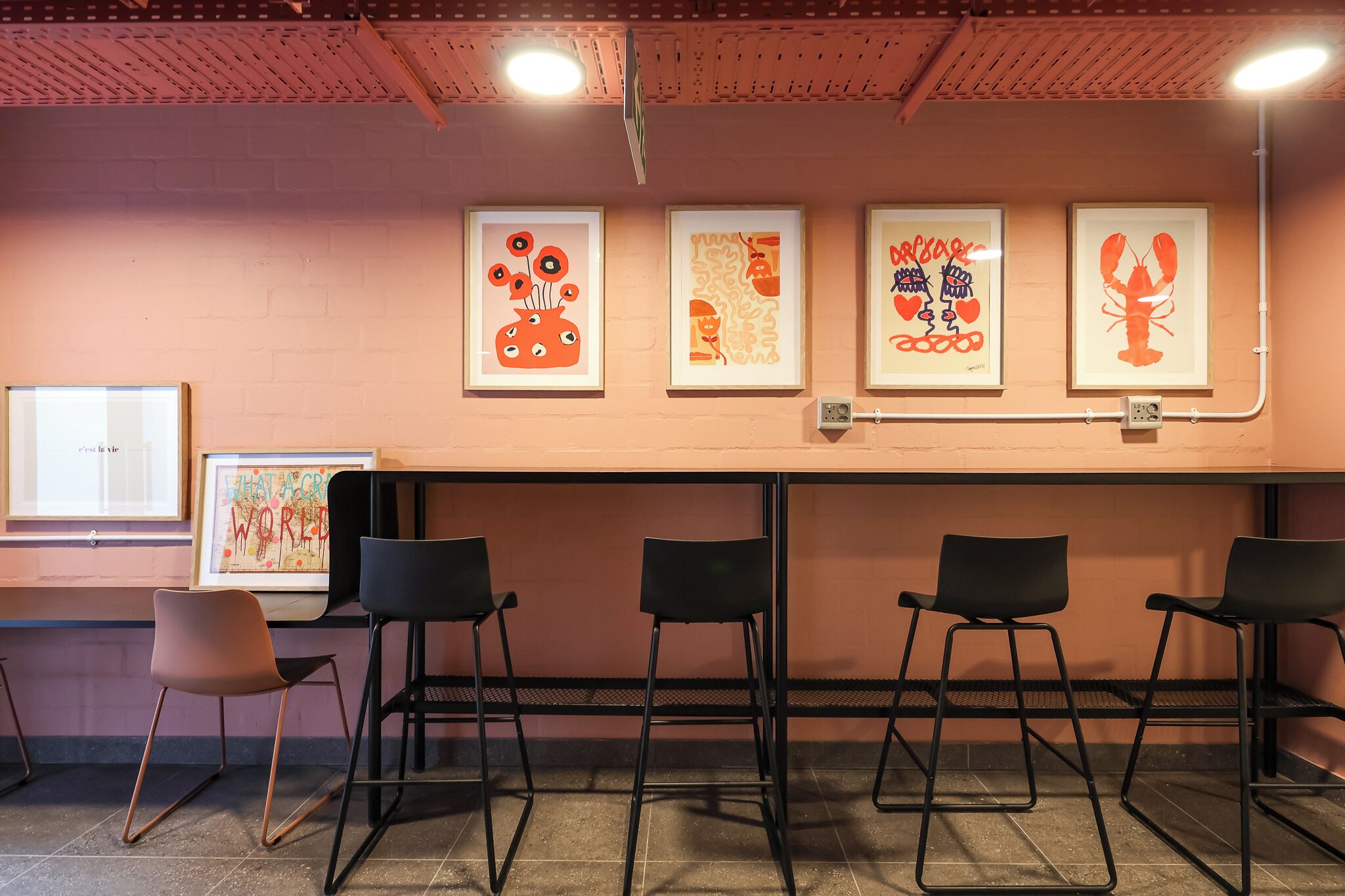 A waiting area with a brick wall, framed artwork, and black chairs.