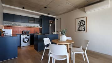 Una cucina funzionale con lavatrice, un'area pranzo con tavolo rotondo e sedie bianche, e un'ampia finestra.
