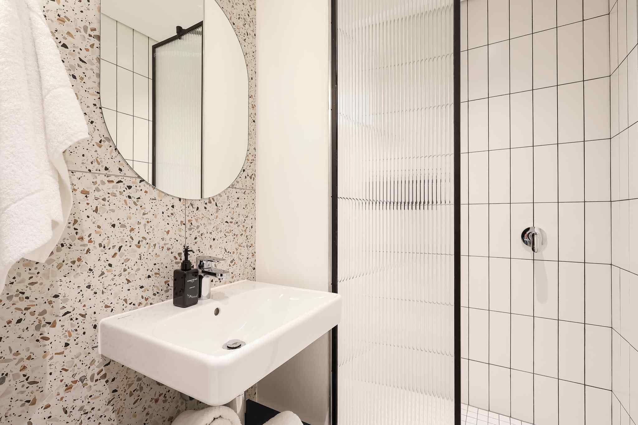 A bathroom with a white sink, a mirror, and a shower area.