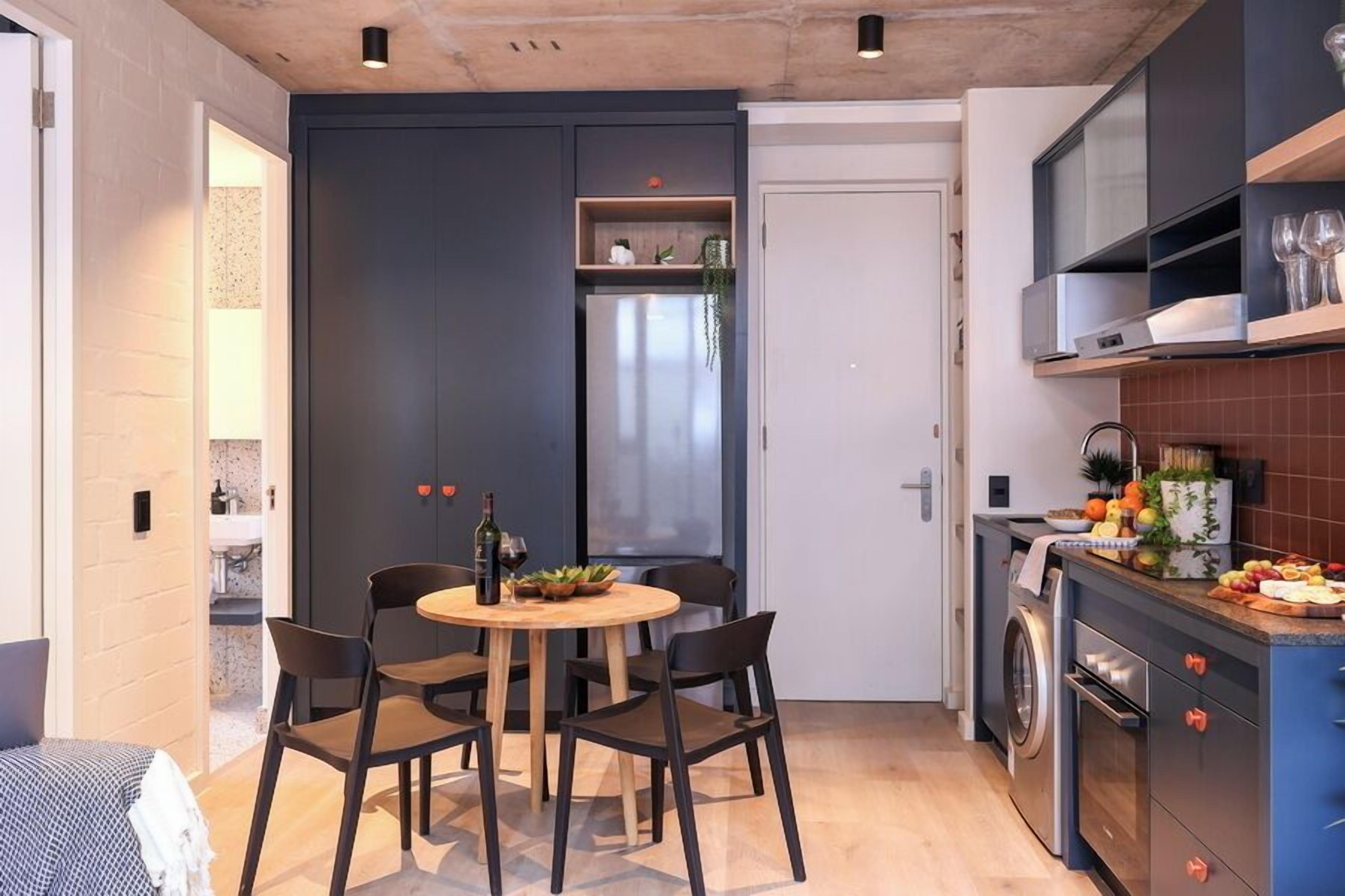 Une cuisine compacte comprenant un coin repas, un lave-linge et un petit réfrigérateur.