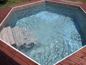 Ein rechteckiges Whirlpool mit umlaufender Holzterrasse.