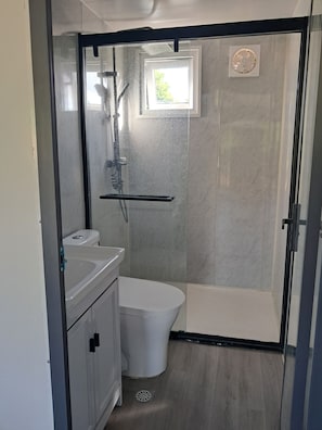A bathroom with a shower, toilet, and sink.