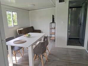 A modern kitchen with a dining table, chairs, a sofa, and a small shelf.