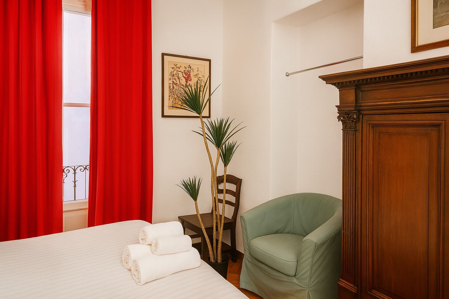 Quarto de hotel com cama, poltrona verde, aparador de madeira e uma planta.