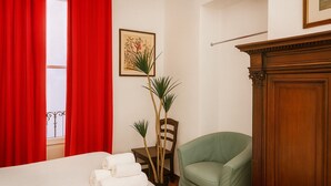 A hotel room with a bed, a green armchair, a wooden cabinet, and a plant. - Casa Milano Vintage Vibes with balcony (Milan)