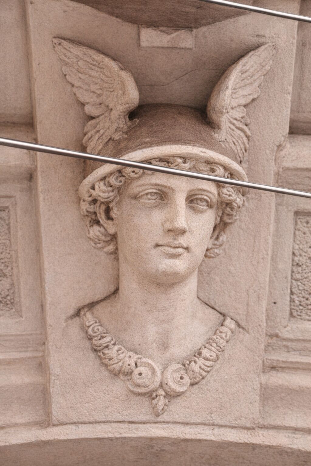 Detalhada escultura em pedra de uma figura com asas e um headdress, provavelmente parte da arquitetura de um edifício.