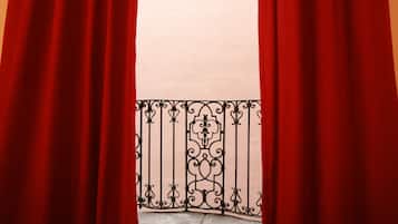 Varanda com cortinas vermelhas e grade de ferro forjado.