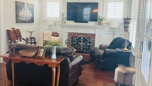 A spacious living room with a fireplace, leather sofas, a wooden coffee table, and a flat-screen TV mounted above the fireplace. - 3-Bed, 3.5-Bath Home Just 4.8 Miles from Golf Course in a Stunning Neighborhood! (Evans)