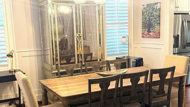 A dining area with a wooden table and chairs, a decorative mirror, and a modern chandelier. - 3-Bed, 3.5-Bath Home Just 4.8 Miles from Golf Course in a Stunning Neighborhood! (Evans)