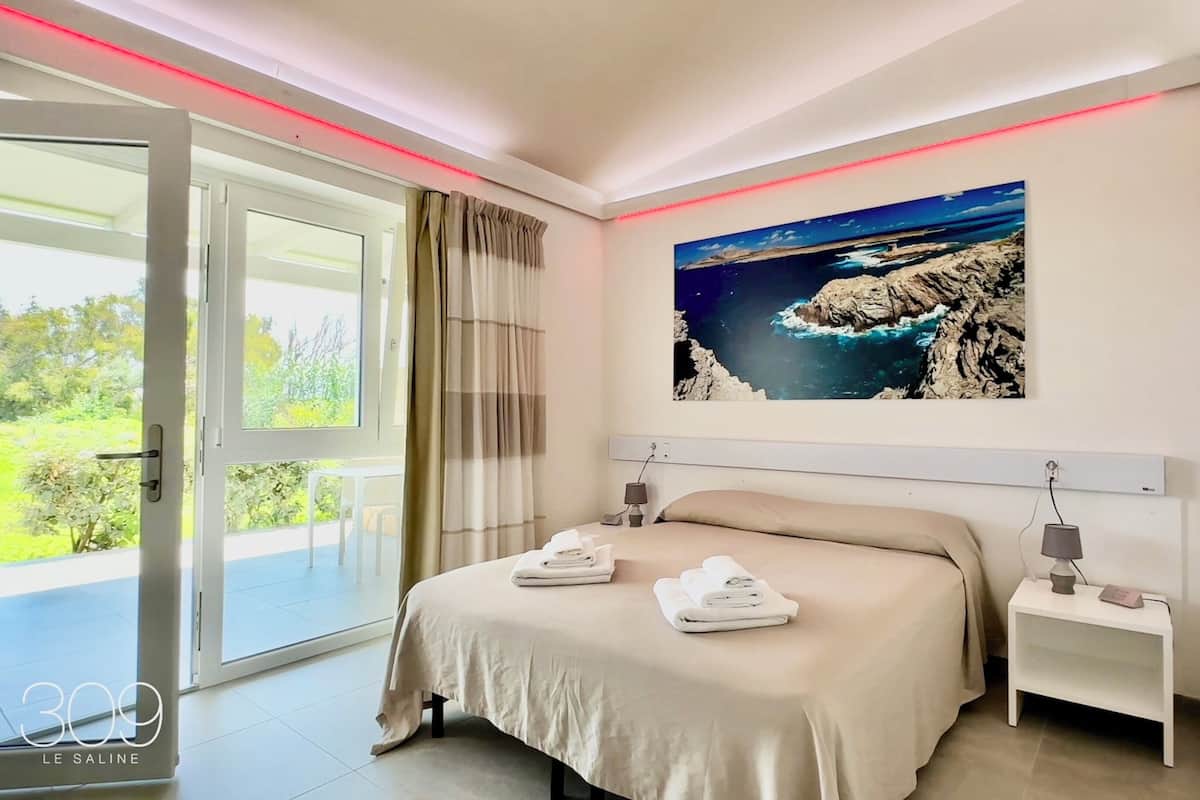Une chambre moderne avec un grand lit, une vue sur l’extérieur et une citation inspirante sur le mur.