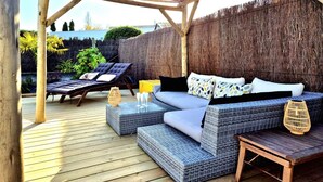 An outdoor patio with a wooden pergola, wicker furniture, and a thatched wall. - Charming villa - Swimming pool - Spa - Pond (Saint-Hilaire-de-Riez)
