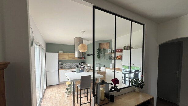 A modern kitchen with a dining area, featuring a large mirror, wooden cabinets, and a view to the outdoors. - Charming villa - Swimming pool - Spa - Pond (Saint-Hilaire-de-Riez)
