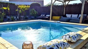 A swimming pool with wooden deck, lounge chairs, and a lantern. - Charming villa - Swimming pool - Spa - Pond (Saint-Hilaire-de-Riez)