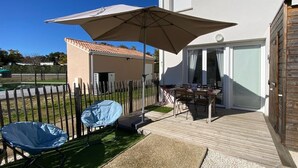 A patio with a table and chairs, a large umbrella, and a covered seating area. - E03, welcoming 3* duplex near ocean & forest (Mimizan)