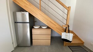 A compact kitchen with a stainless steel refrigerator, wooden drawers, and a wooden staircase. - E03, welcoming 3* duplex near ocean & forest (Mimizan)