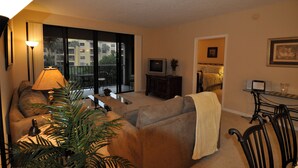 A living room with a sofa, a TV, a lamp, and a balcony. - Lake Front 3-bedroom condo walk to Nextera and beach in Juno Beach (JUNO BEACH)