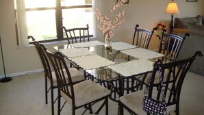 A dining area with a glass table, chairs, and a vase with flowers. - Lake Front 3-bedroom condo walk to Nextera and beach in Juno Beach (JUNO BEACH)