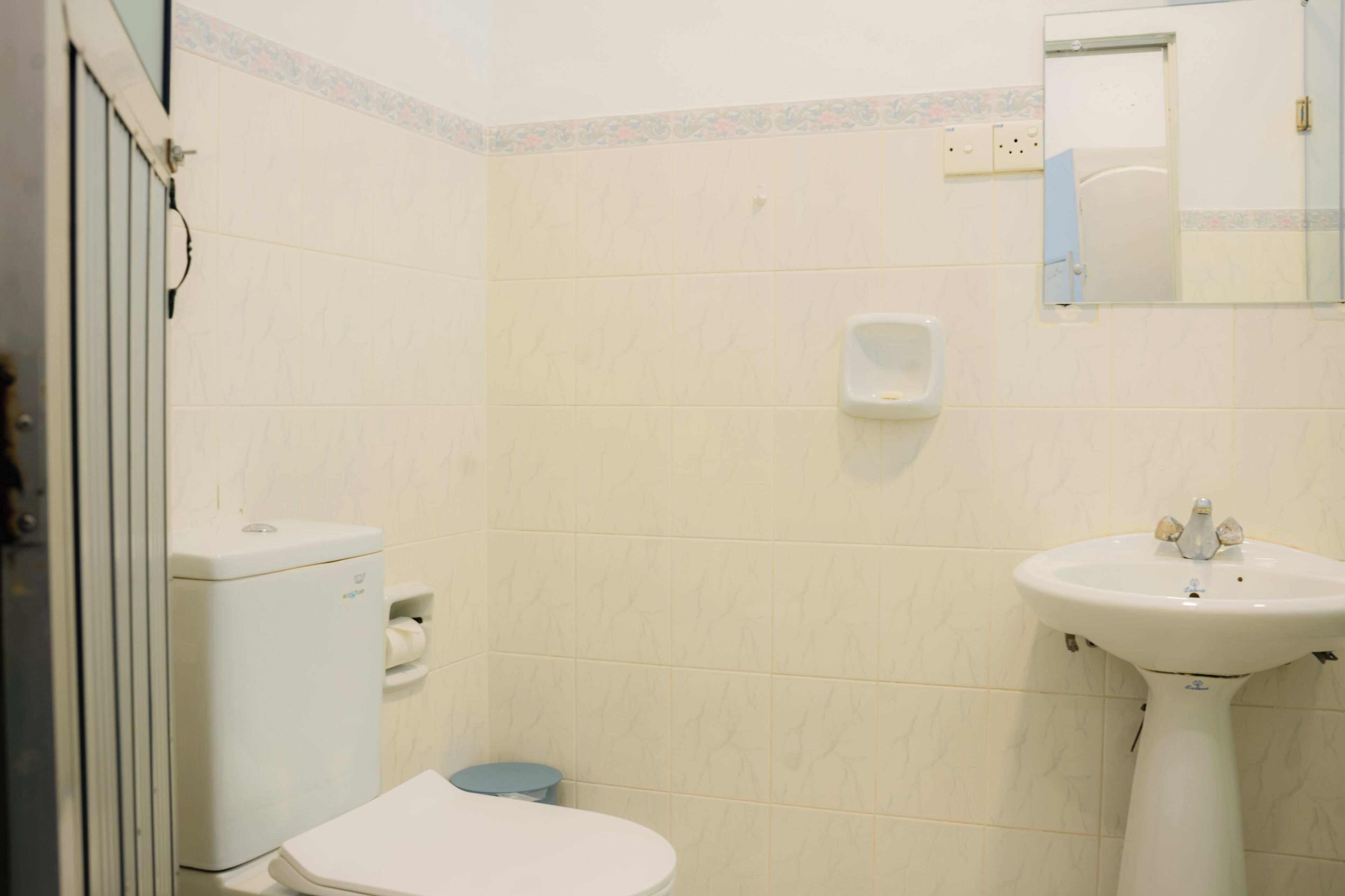 A small bathroom with a toilet, a sink, and a mirror.
