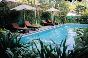 Un área de piscina con sillones y sombrillas.