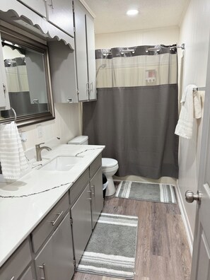 Un baño pequeño con lavamanos, inodoro y ducha.