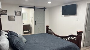 Een slaapkamer met een bed, een dressoir, een televisie en een schuifdeur.