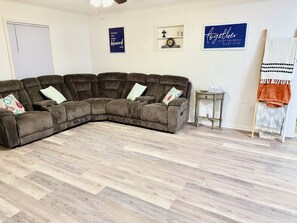 Un sofá modular con varios cojines, una mesita auxiliar y una pared con dos letreros.