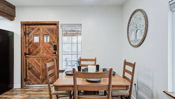 A dining area with a wooden table and chairs, a window with a view, and a decorative tree wall art piece.