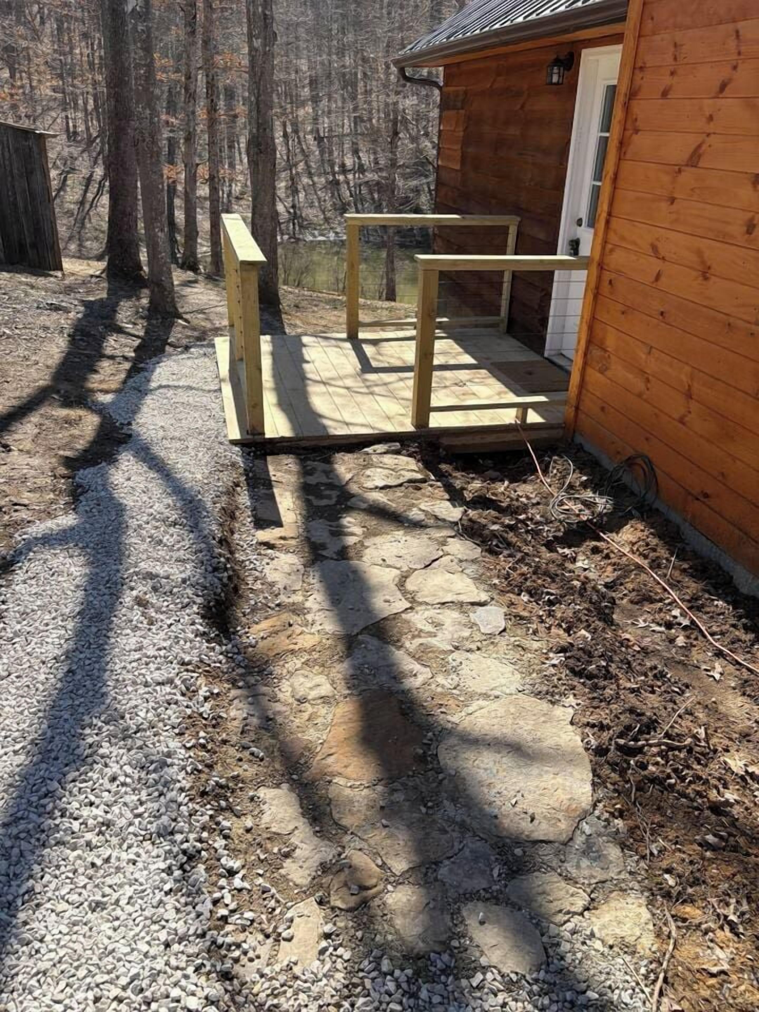 A wooden cabin with a gravel pathway leading to a wooden deck.