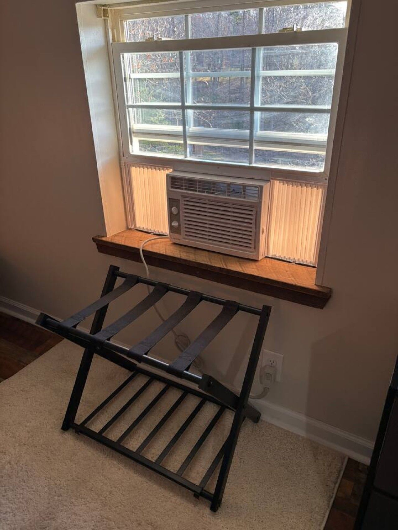 Una habitación con ventana, radiador y una estantería metálica.